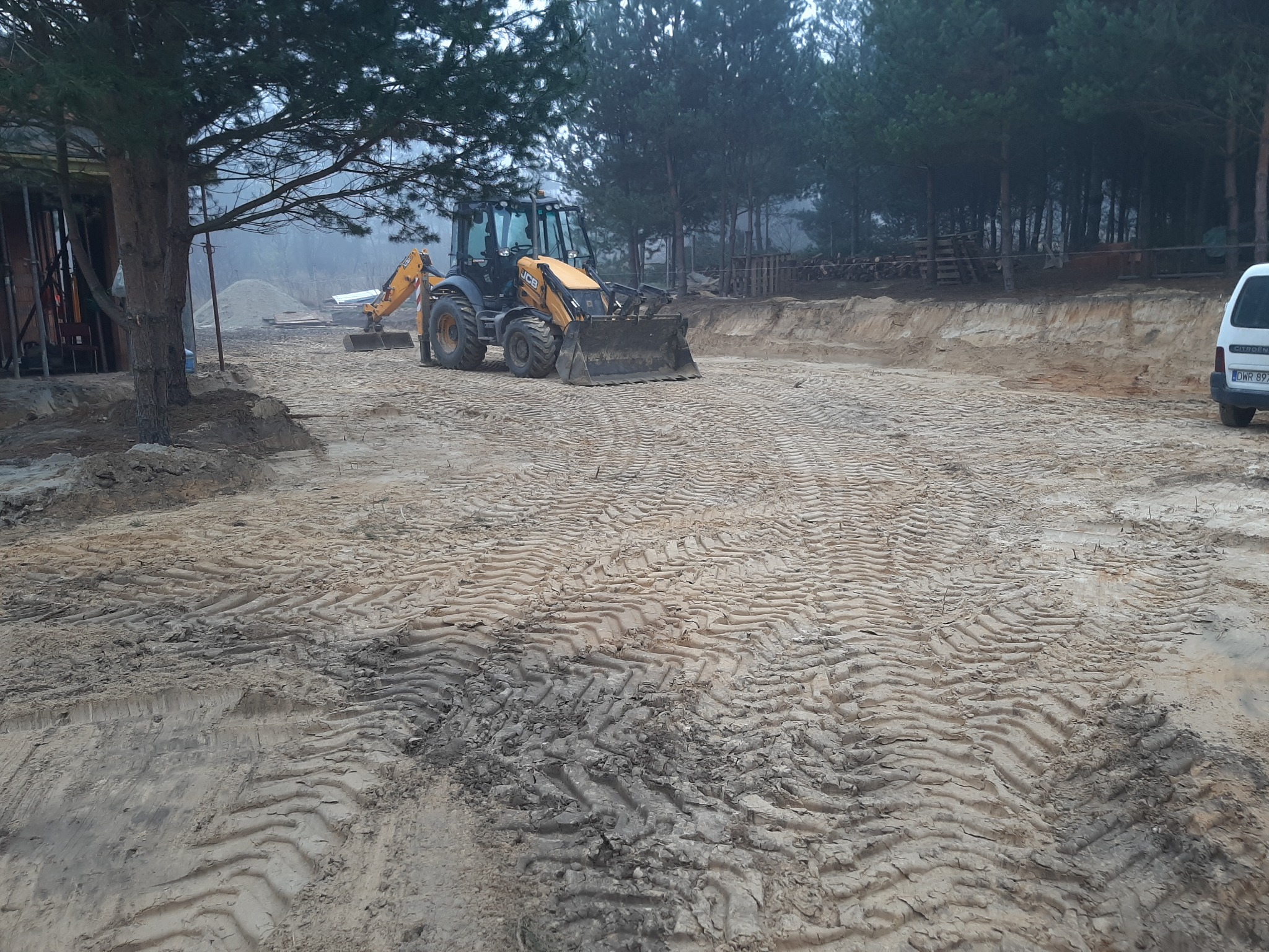 Koparko-ładowarka JCB DIG UP podczas prac na działce